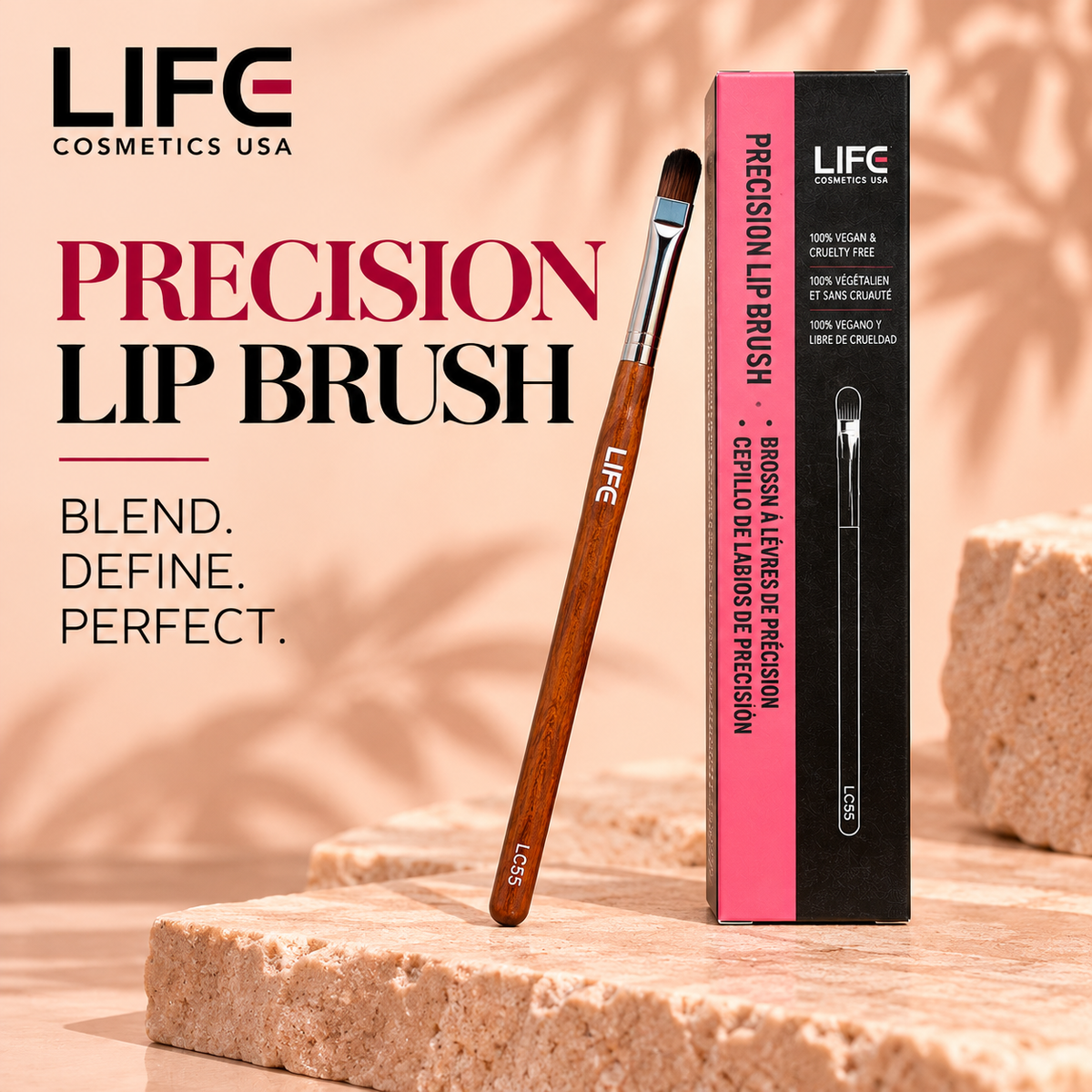 LIFE Cosmetics USA LC55 Precision Lip Brush with rounded dark bristles, a silver ferrule and wooden handle leaning beside its upright pink-and-black box on a peach stone surface.