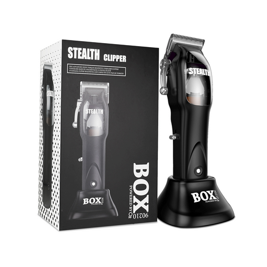 Black BOX90210 STEALTH clipper with silver blades standing in its charging base beside the branded retail box on white.