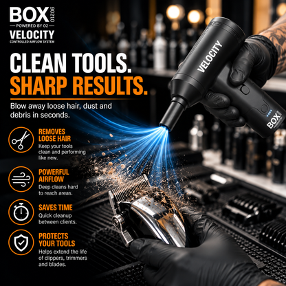 Gloved hands using BOX90210 VELOCITY with a narrow nozzle to blow loose hair and debris from clipper blades in a barbershop.
