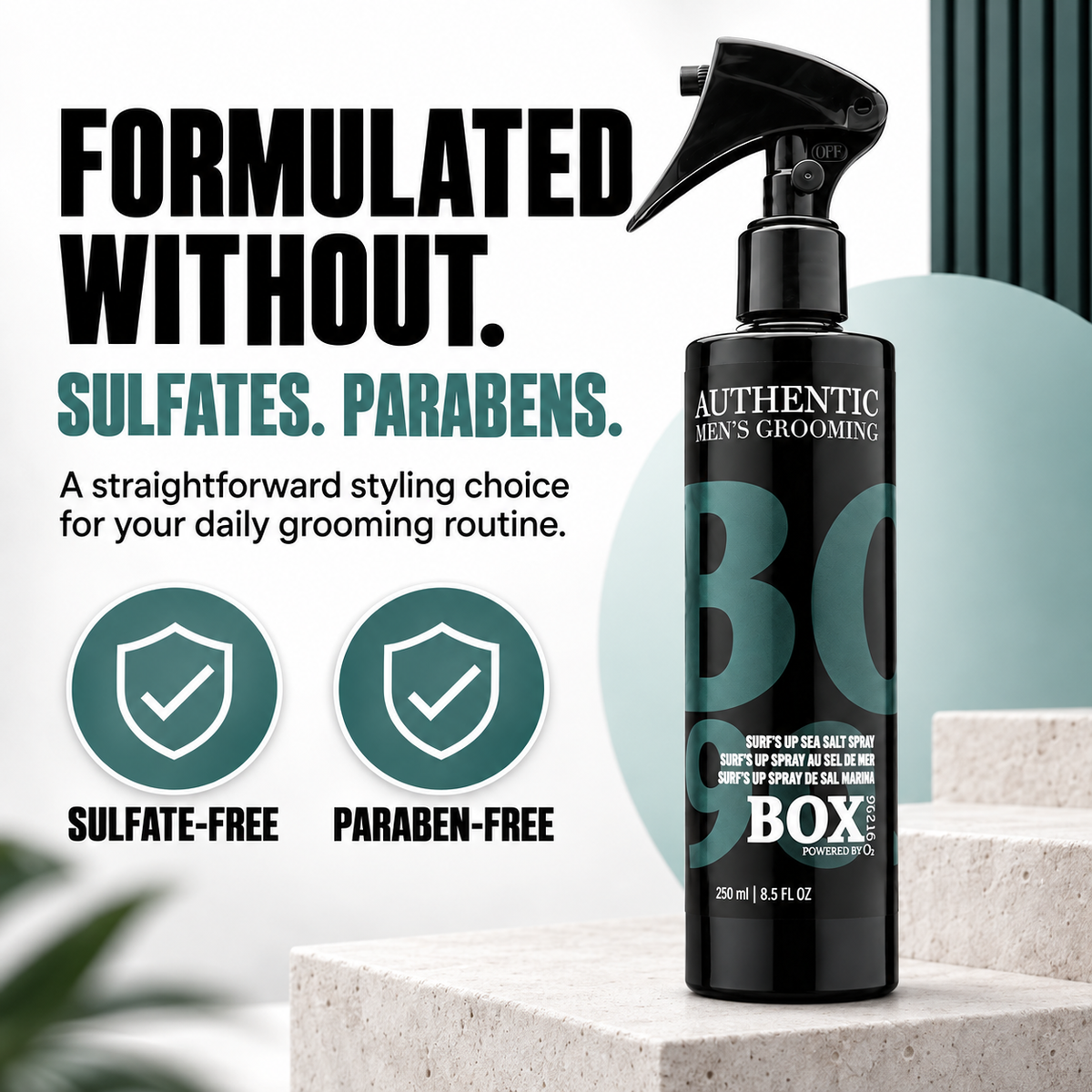 BOX90210 Surf’s Up Sea Salt Spray bottle on a light stone platform beside teal shield icons labeled sulfate-free and paraben-free.