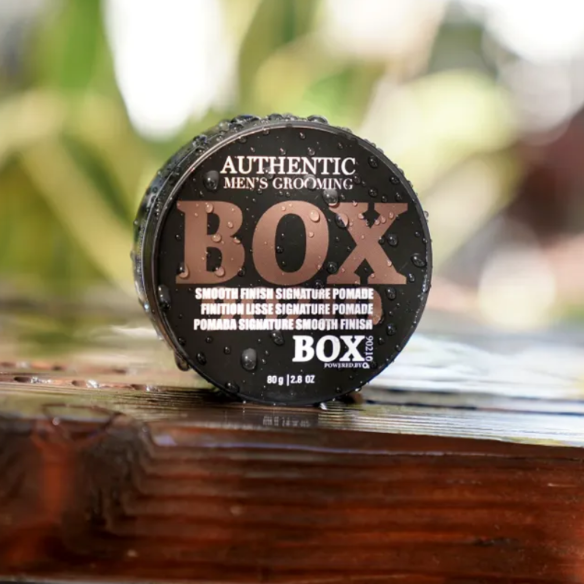 Men's grooming product container on a wooden surface with a blurred natural background