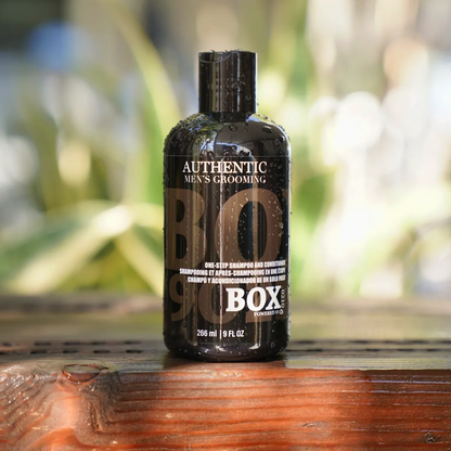 Bottle of 'Authentic Men's Grooming' on a wooden surface with a blurred natural background