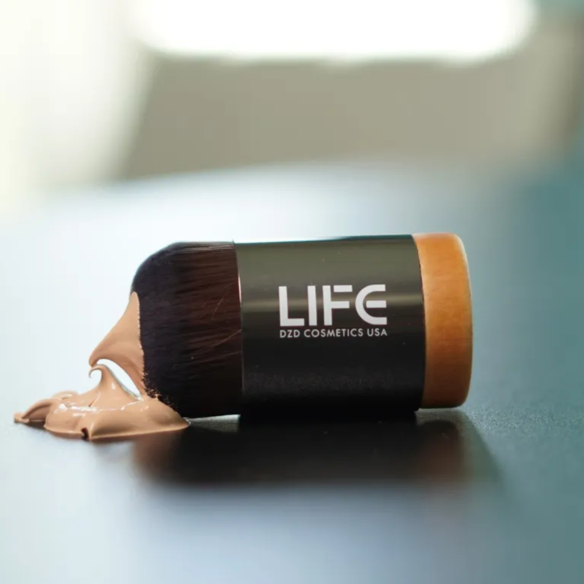 Makeup brush with brown makeup on a blurred background