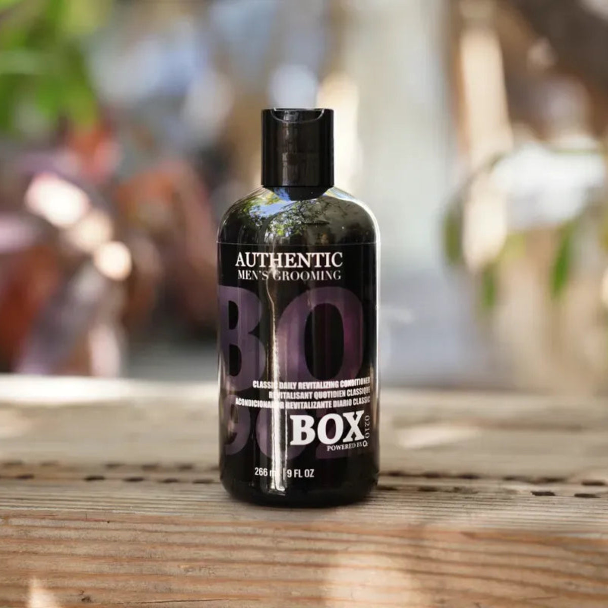 Bottle of 'Authentic Men's Grooming' product on a wooden surface with a blurred natural background