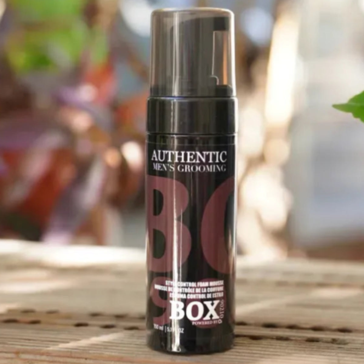 Mousse bottle with 'BO' branding on a wooden surface outdoors